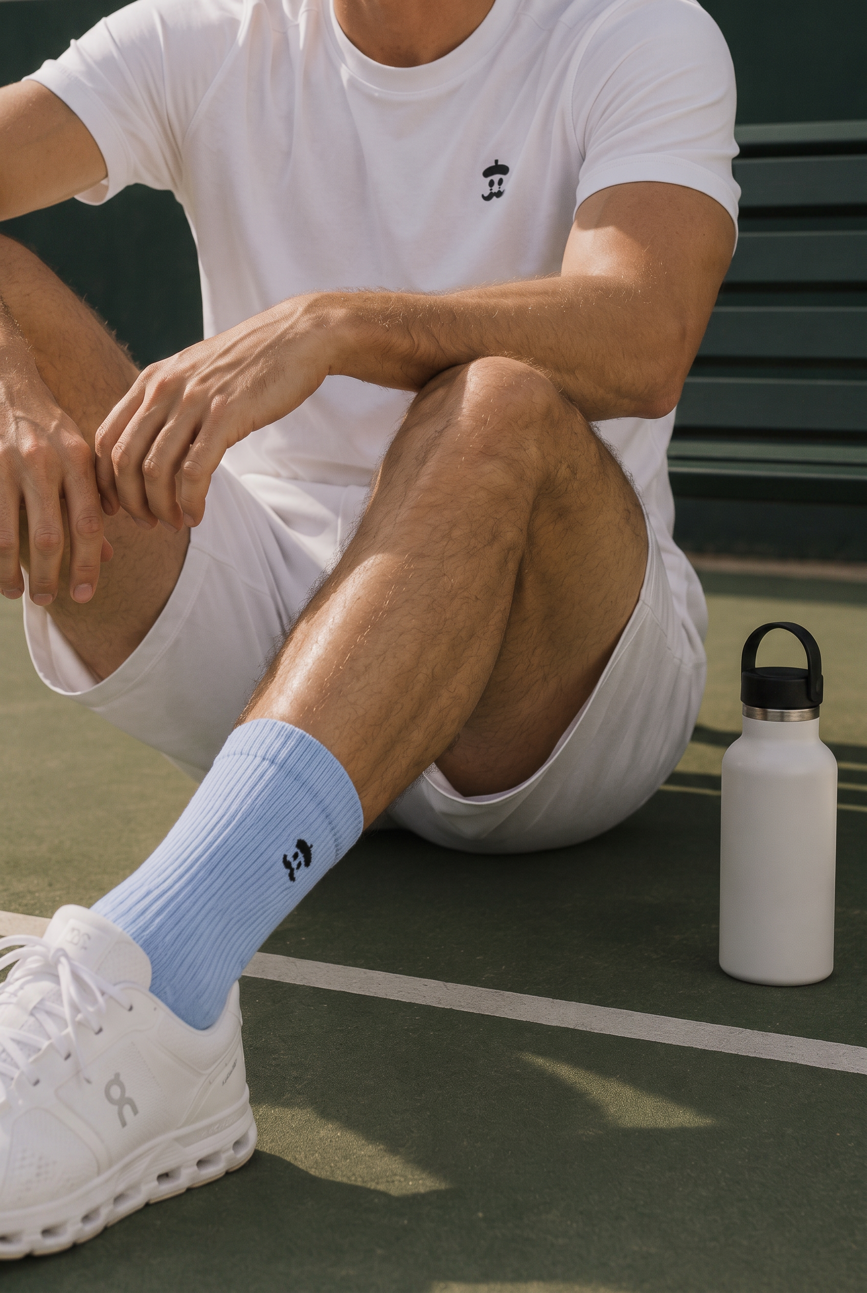 Sky blue Sockrebleu socks with white sneakers on a tennis court